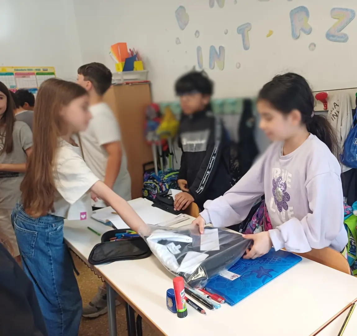 Passaggio di consegne solidale al Convitto Leopardi, un'alunna di quinta dona il proprio grembiule a una compagna di terza, promuovendo il riuso